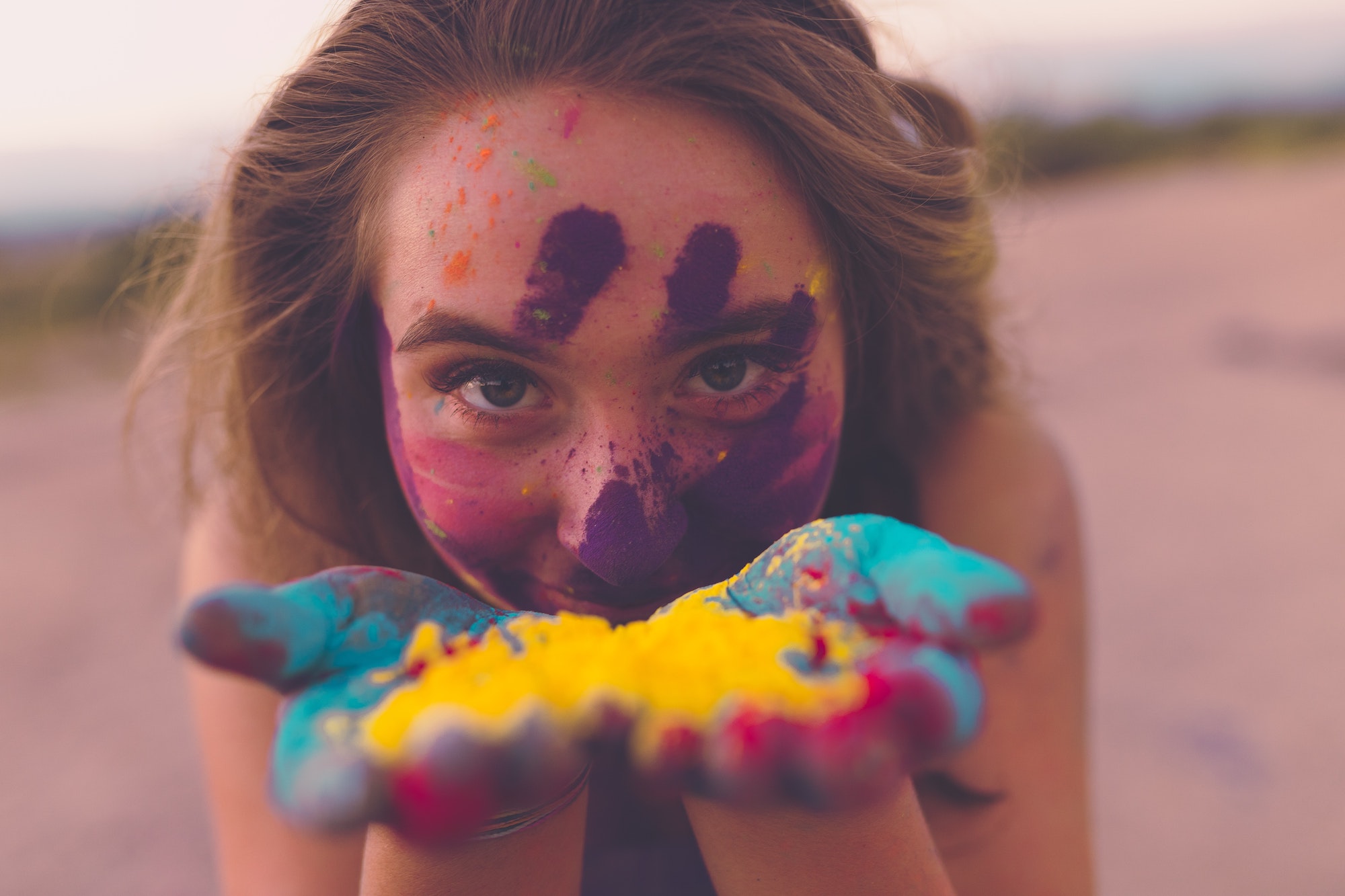 Une jeune femme avec de la peinture colorée sur les mains et le visage