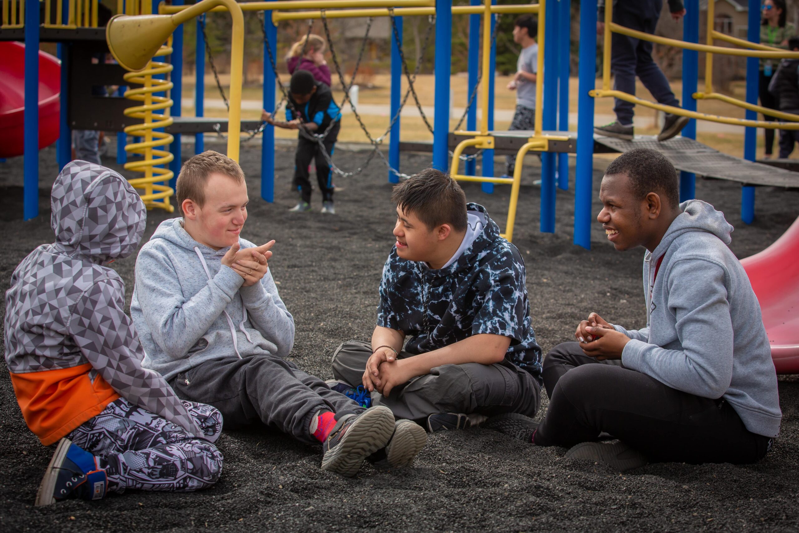 Quatre personnes assises par terre dans une aire de jeux.