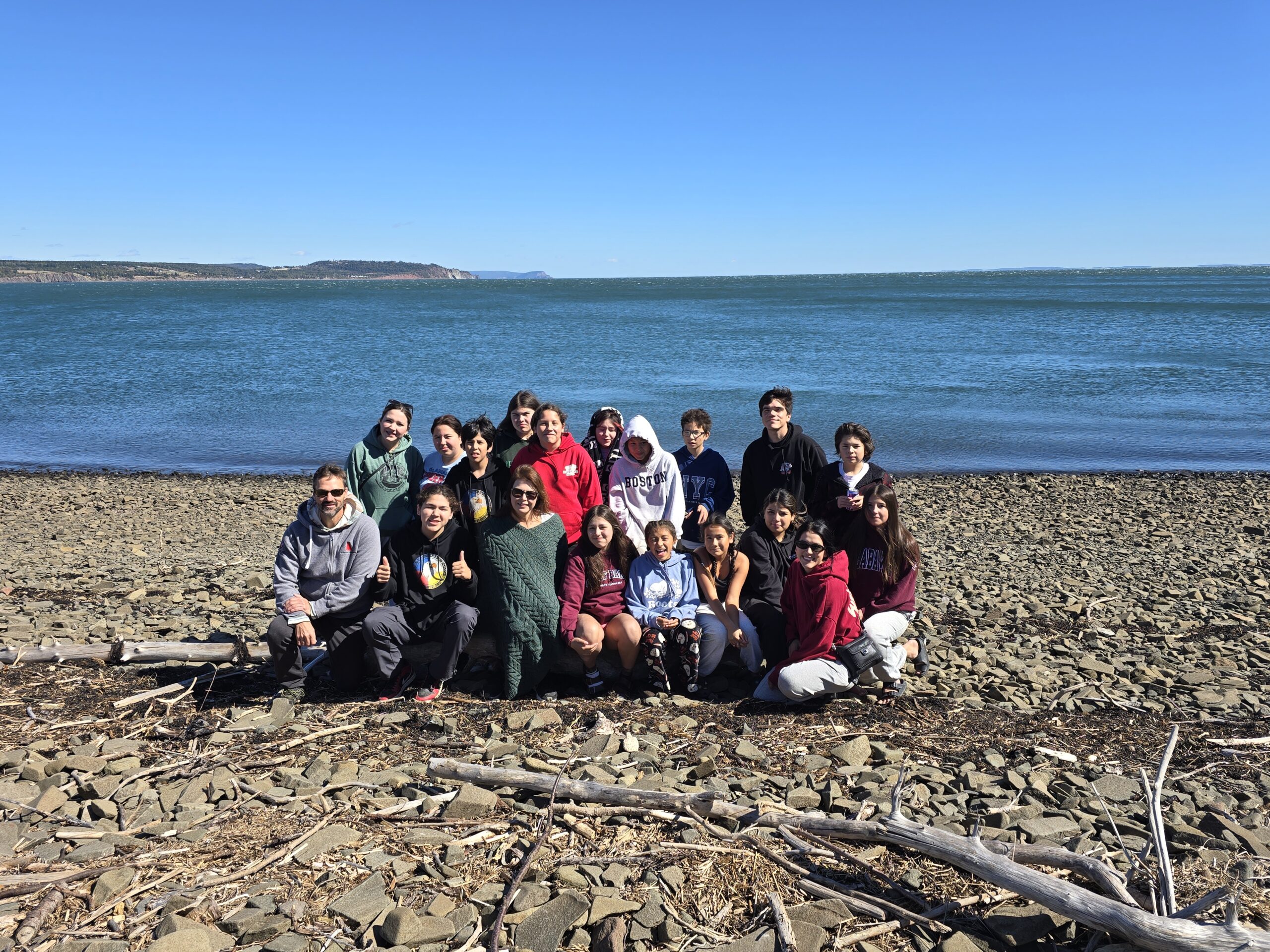 Un groupe de personnes pose au bord de l'eau par une journée ensoleillée.